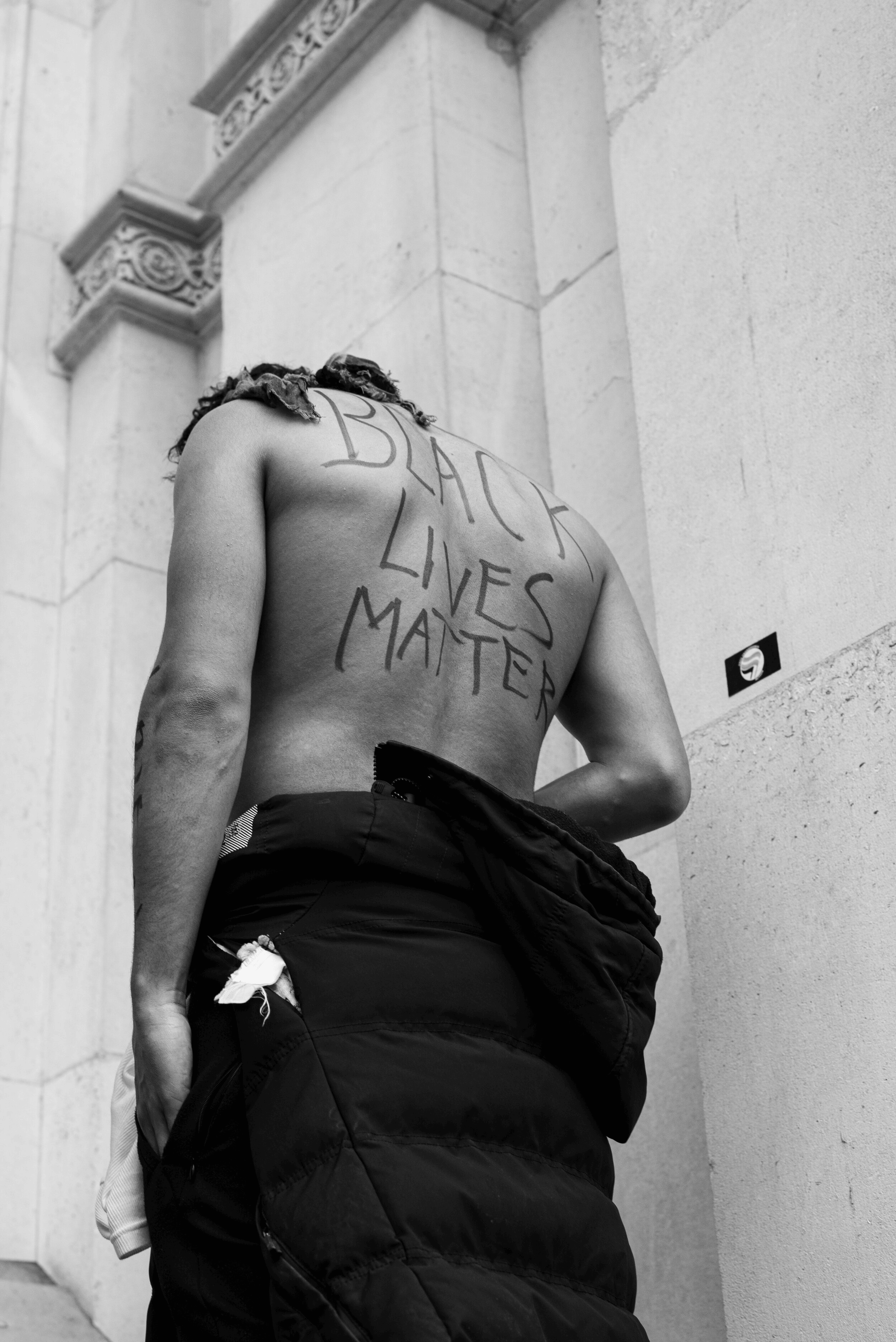 London BLM March’by Jai Toor, 2020 Protestor with ‘Black Lives Matter’ on his back
